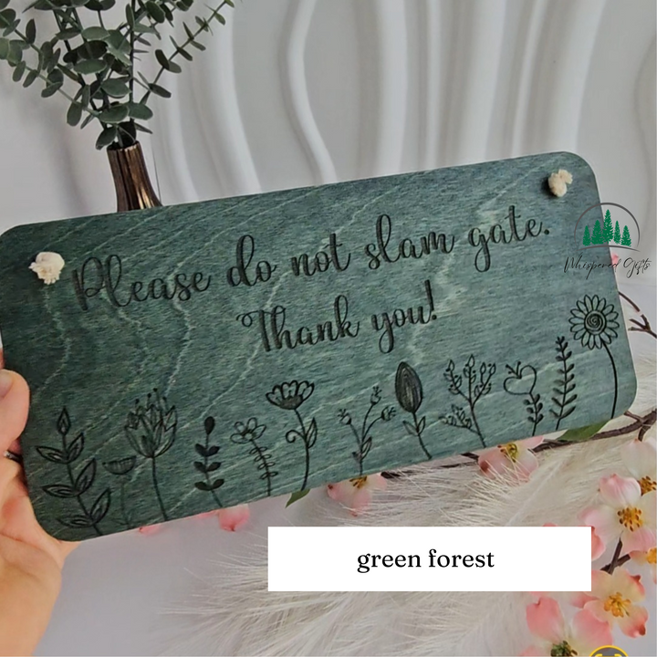 a wooden sign with a message about not damaging the gate, surrounded by flowers and greenery.